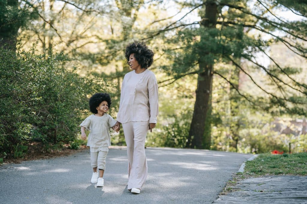 a person and a child laughing and walking on a path with evergreen trees depicting the vibrant lifestyle at Flora apartments in summerville sc - pexels barbara olsen 7880598